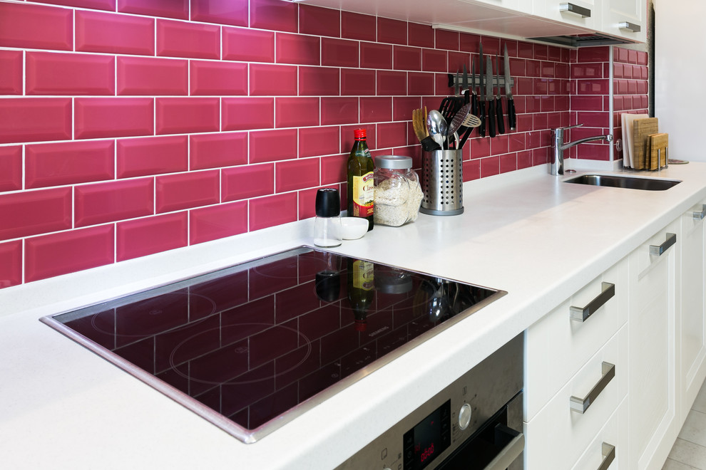 Mid-sized transitional single-wall open plan kitchen in Other with an integrated sink, raised-panel cabinets, white cabinets, solid surface benchtops, red splashback, subway tile splashback, no island and white benchtop.