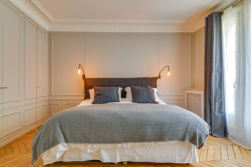 This is an example of a transitional master bedroom in Paris with grey walls, light hardwood floors and beige floor.