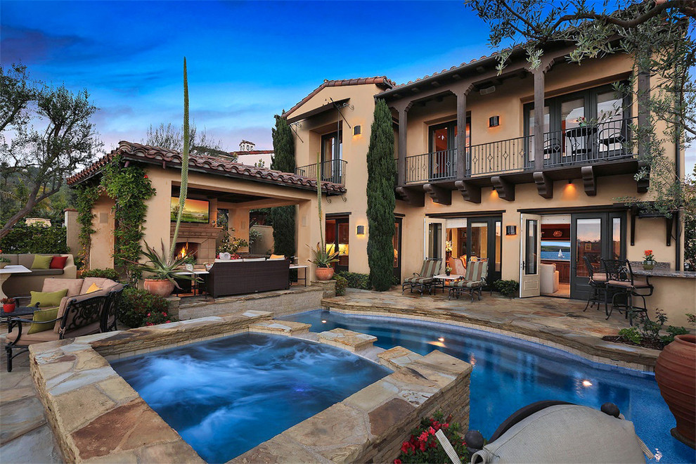 This is an example of a mid-sized mediterranean two-storey stucco beige house exterior in Orange County with a tile roof.