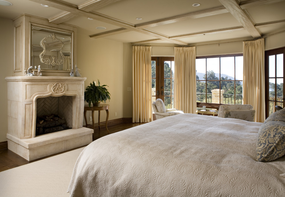 Design ideas for a mediterranean master bedroom in Other with beige walls, dark hardwood floors and a standard fireplace.
