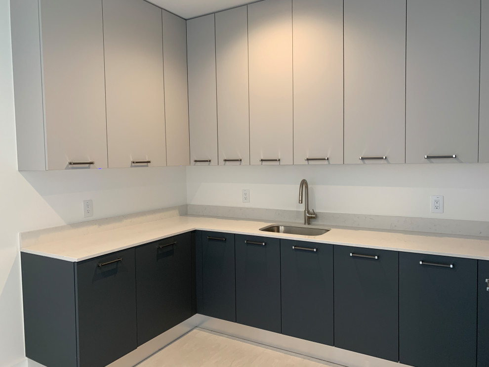 This is an example of a mid-sized modern u-shaped utility room in Austin with a drop-in sink, flat-panel cabinets, laminate benchtops, white splashback, ceramic splashback, white walls, light hardwood floors, a concealed washer and dryer, white floor and white benchtop.