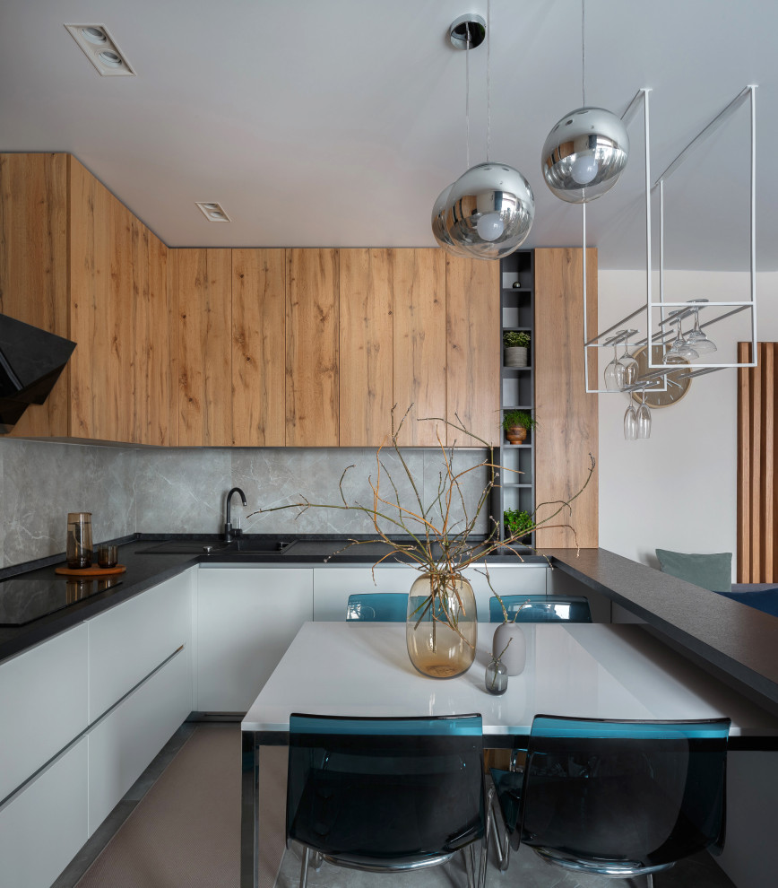 Design ideas for a contemporary l-shaped kitchen in Other with a drop-in sink, flat-panel cabinets, medium wood cabinets, grey splashback, stone slab splashback, with island, grey floor and black benchtop.