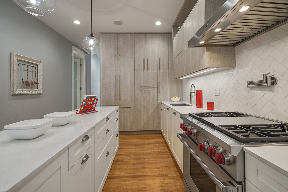Kitchen - mid-sized transitional l-shaped medium tone wood floor and brown floor kitchen idea in San Francisco with an undermount sink, flat-panel cabinets, white cabinets, quartz countertops, white backsplash, marble backsplash, an island, white countertops and stainless steel appliances