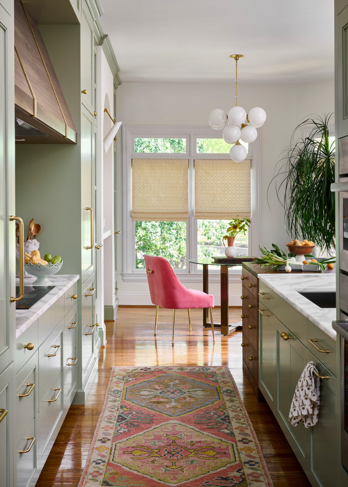 Inspiration for a mid-sized transitional galley medium tone wood floor and brown floor open concept kitchen remodel in Atlanta with an undermount sink, recessed-panel cabinets, green cabinets, marble countertops, white backsplash, marble backsplash, paneled appliances, an island and white countertops