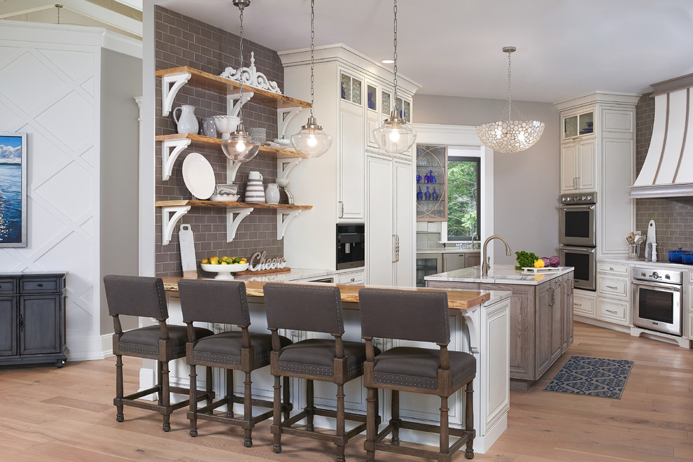 Beach style light wood floor and beige floor kitchen photo in Grand Rapids with raised-panel cabinets, white cabinets, quartzite countertops, gray backsplash, a single-bowl sink, subway tile backsplash, stainless steel appliances and a peninsula