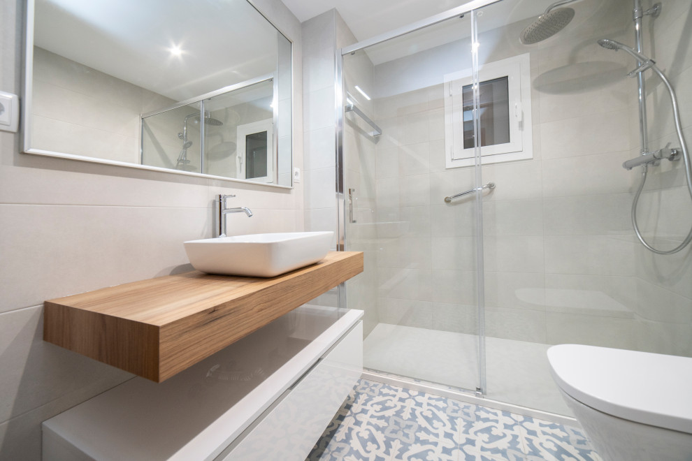 Design ideas for a mid-sized contemporary master bathroom in Barcelona with flat-panel cabinets, dark wood cabinets, a curbless shower, a one-piece toilet, white tile, ceramic tile, ceramic floors, a vessel sink, wood benchtops, blue floor, a sliding shower screen, brown benchtops, an enclosed toilet, a single vanity and a floating vanity.