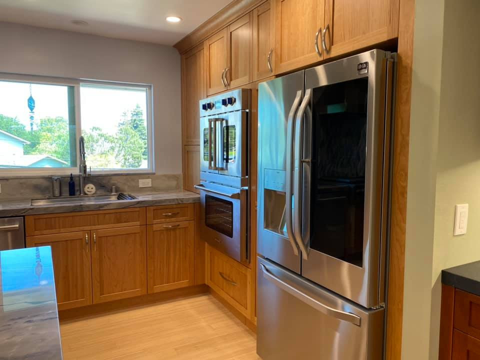 Foto på ett stort amerikanskt grå kök, med en undermonterad diskho, skåp i shakerstil, skåp i mellenmörkt trä, bänkskiva i kvartsit, grått stänkskydd, stänkskydd i glaskakel, rostfria vitvaror, bambugolv, en halv köksö och gult golv