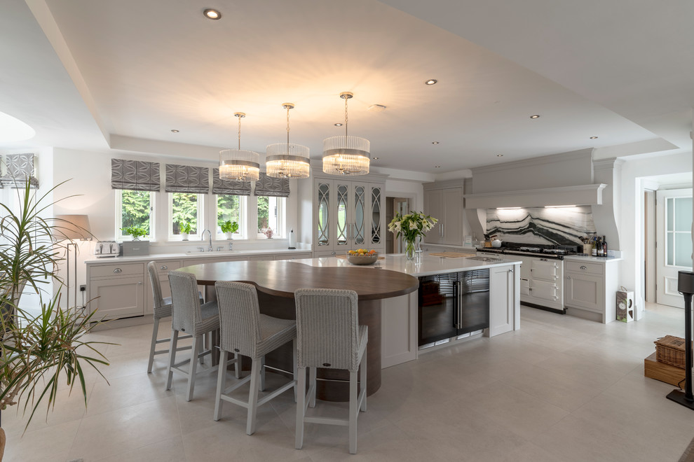 Expansive transitional l-shaped kitchen in Cheshire with shaker cabinets, grey cabinets, wood benchtops, black splashback, white appliances, with island, white floor and brown benchtop.