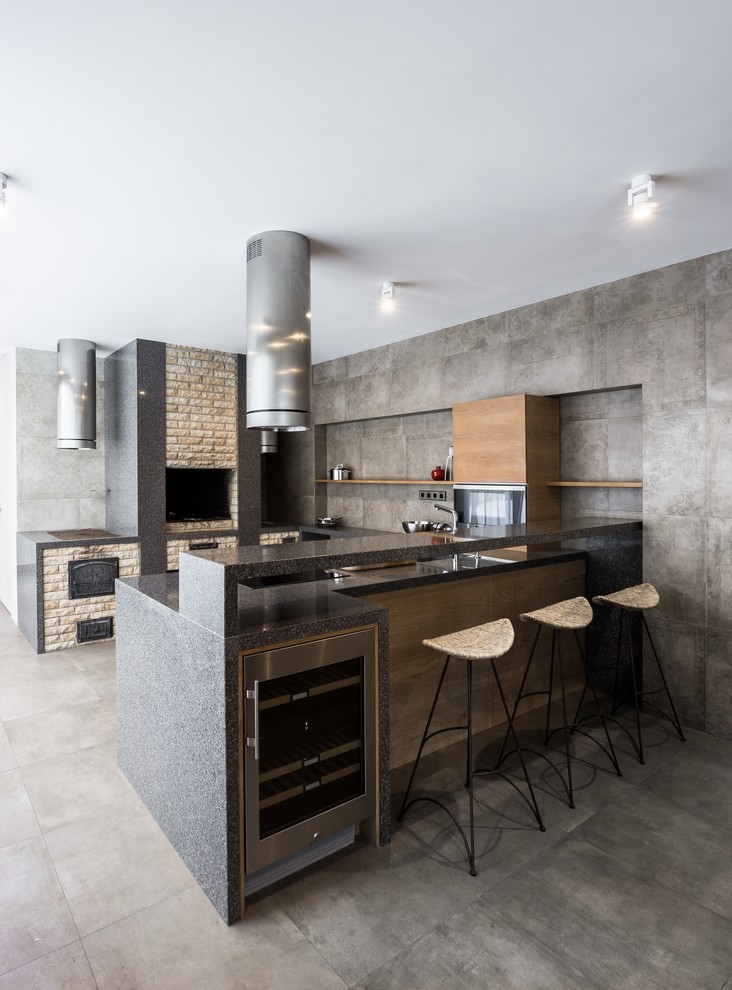 This is an example of an industrial u-shaped kitchen in Moscow with flat-panel cabinets, medium wood cabinets, grey splashback, stainless steel appliances, grey floor and grey benchtop.