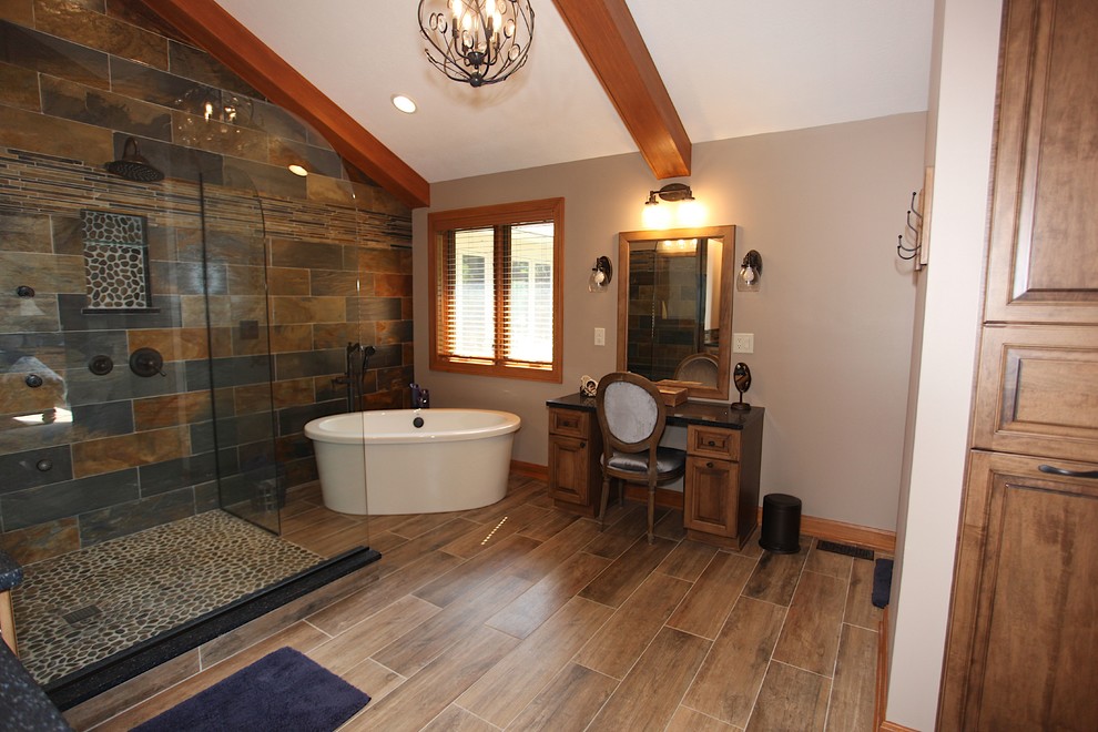 Freestanding bathtub - large rustic master slate tile brown floor freestanding bathtub idea in Indianapolis with brown cabinets, beige walls and an undermount sink