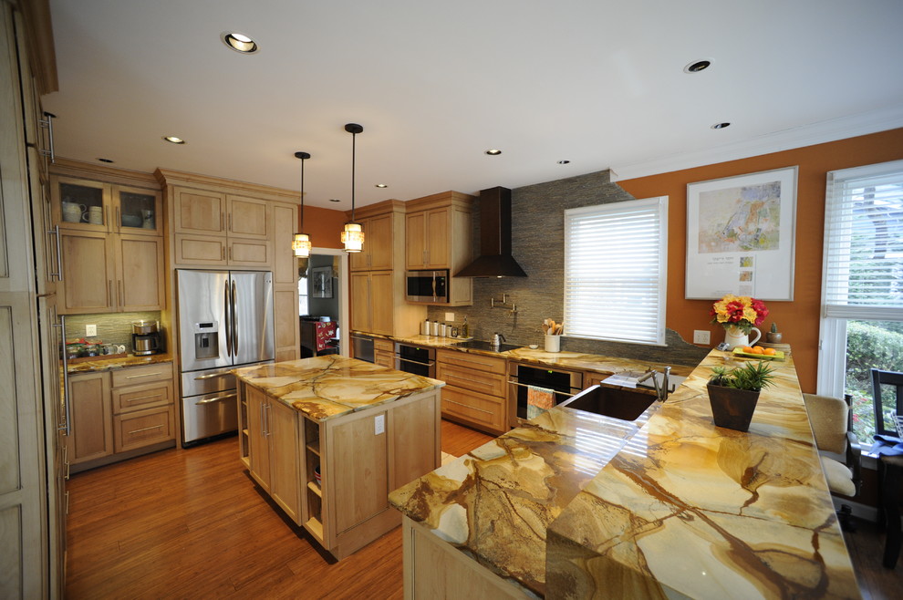 Example of a mid-sized transitional u-shaped light wood floor eat-in kitchen design in Baltimore with a farmhouse sink, light wood cabinets, onyx countertops, stainless steel appliances, an island and beaded inset cabinets