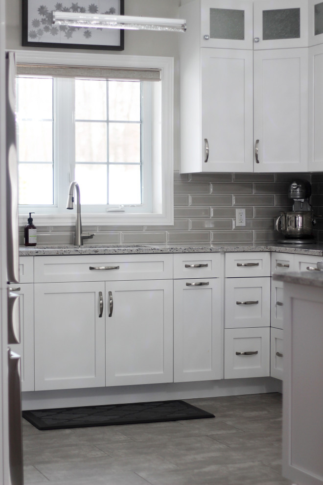 Kitchen - small u-shaped vinyl floor and green floor kitchen idea with an undermount sink, shaker cabinets, white cabinets, quartzite countertops, gray backsplash, subway tile backsplash, stainless steel appliances, a peninsula and gray countertops