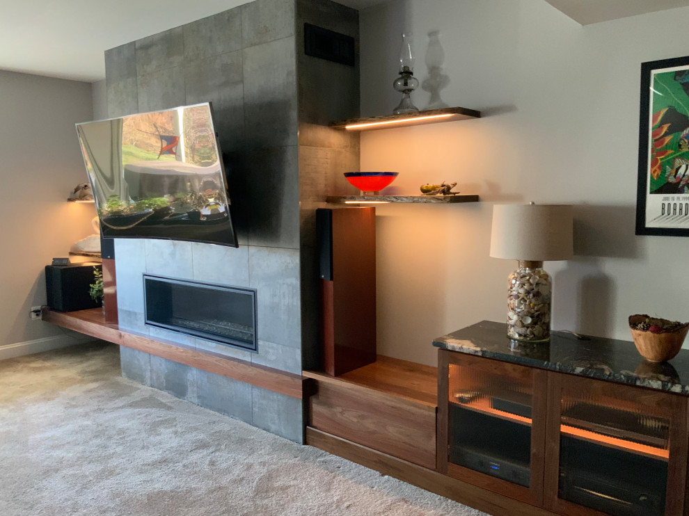 Cette image montre un sous-sol minimaliste donnant sur l'extérieur et de taille moyenne avec un mur gris, moquette, une cheminée ribbon, un manteau de cheminée en carrelage et un sol beige.