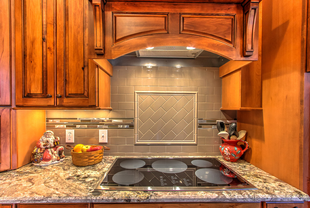 Example of a mountain style kitchen design with raised-panel cabinets, granite countertops, subway tile backsplash and an island