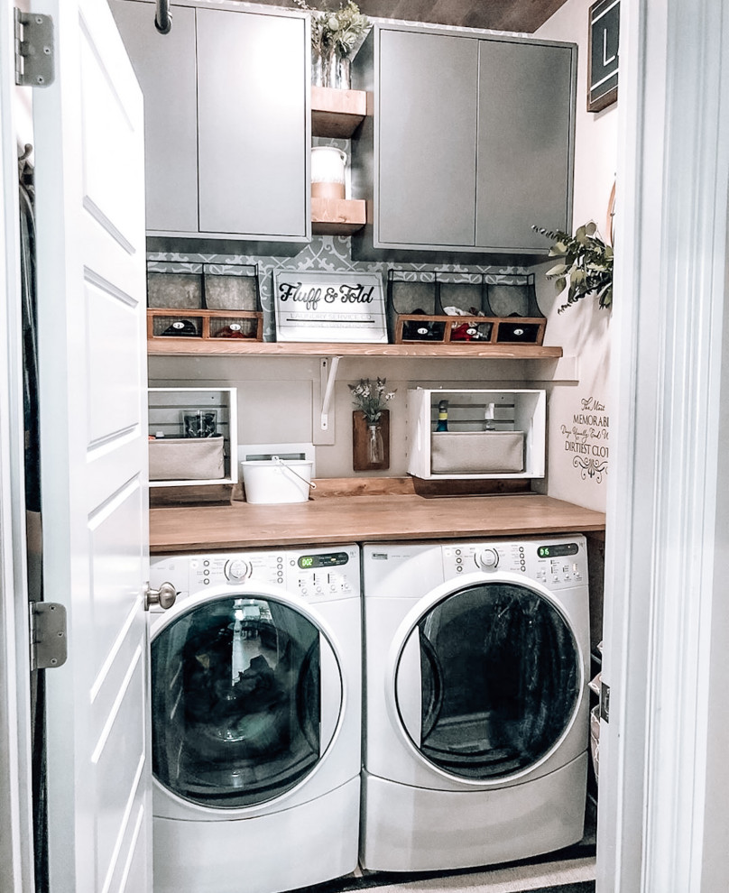 Inspiration for a small single-wall laundry cupboard in Dallas with grey cabinets, wood benchtops, beige walls, ceramic floors, a side-by-side washer and dryer, white floor, brown benchtop and wood.