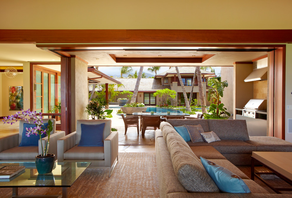 Tropical open concept living room in Hawaii with yellow walls and slate floors.