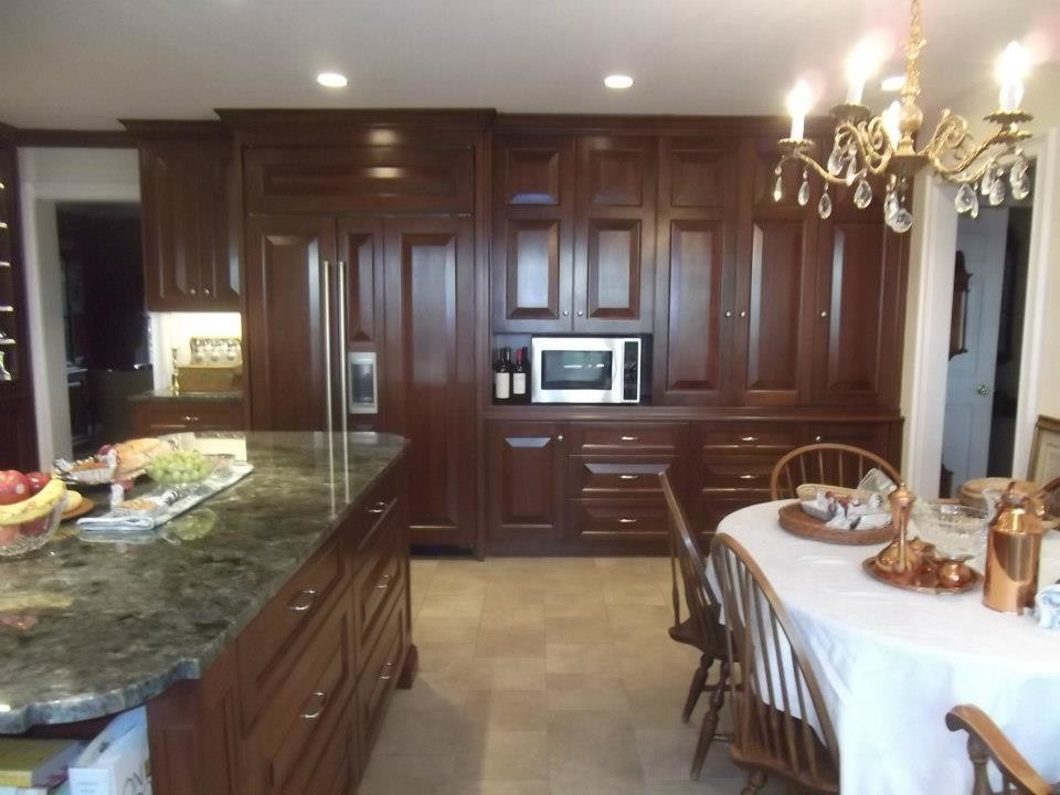 Large traditional l-shaped eat-in kitchen in Philadelphia with raised-panel cabinets, dark wood cabinets, quartzite benchtops, panelled appliances, porcelain floors, with island, white splashback, ceramic splashback and green floor.
