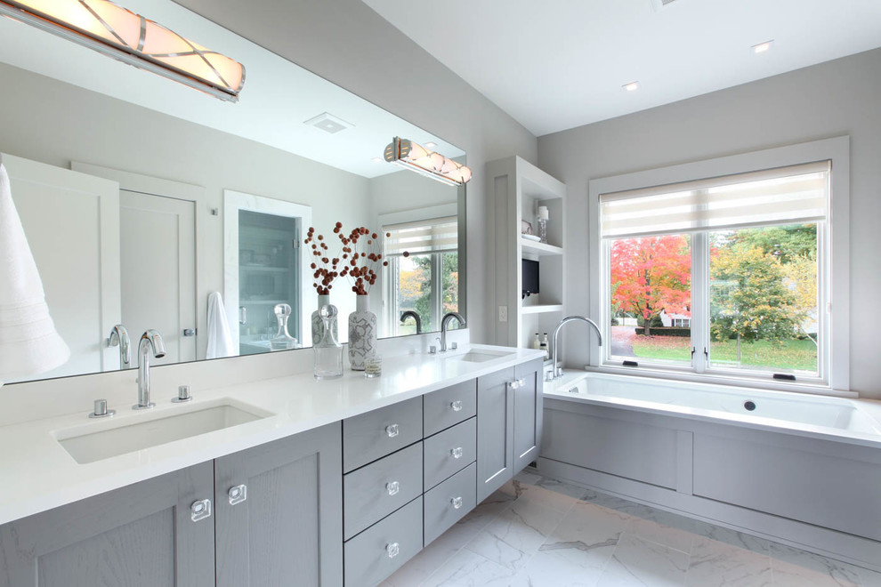 This is an example of a mid-sized transitional master bathroom in Grand Rapids with an undermount sink, shaker cabinets, grey cabinets, quartzite benchtops, porcelain tile, grey walls, porcelain floors and an undermount tub.