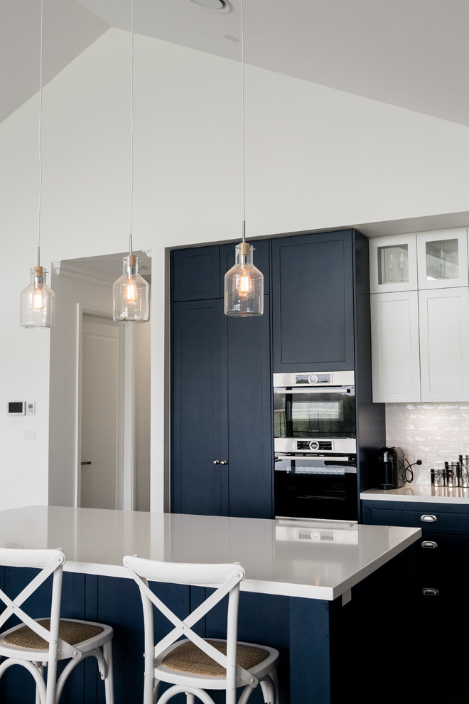 Design ideas for a large beach style kitchen in Newcastle - Maitland with an undermount sink, shaker cabinets, blue cabinets, quartz benchtops, white splashback, stainless steel appliances, with island and white benchtop.