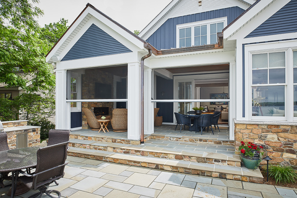 This is an example of a small coastal stone screened-in back porch design in Grand Rapids with a roof extension.