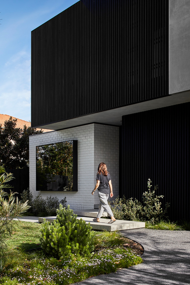 Mid-sized modern two-storey black house exterior in Melbourne with wood siding, a flat roof and a metal roof.