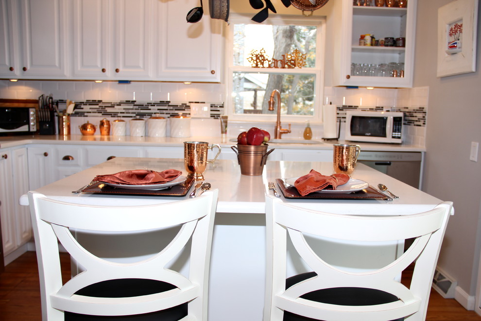 Inspiration for a mid-sized transitional l-shaped light wood floor eat-in kitchen remodel in Denver with raised-panel cabinets, white cabinets, stainless steel appliances, an island, an undermount sink, quartz countertops, multicolored backsplash and glass tile backsplash