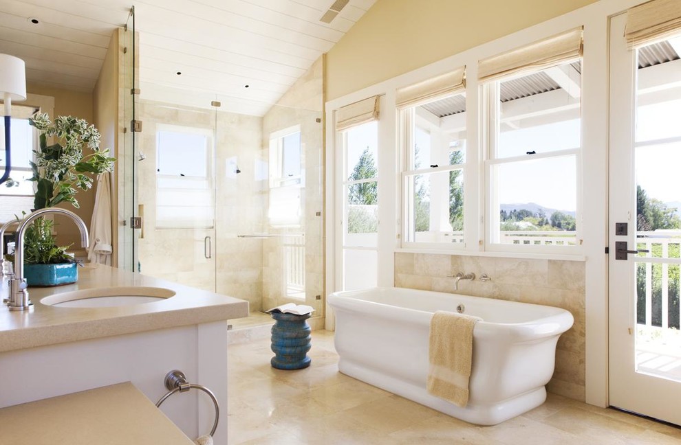 Country master bathroom in San Francisco with an undermount sink, a freestanding tub, a curbless shower, beige tile and beige walls.