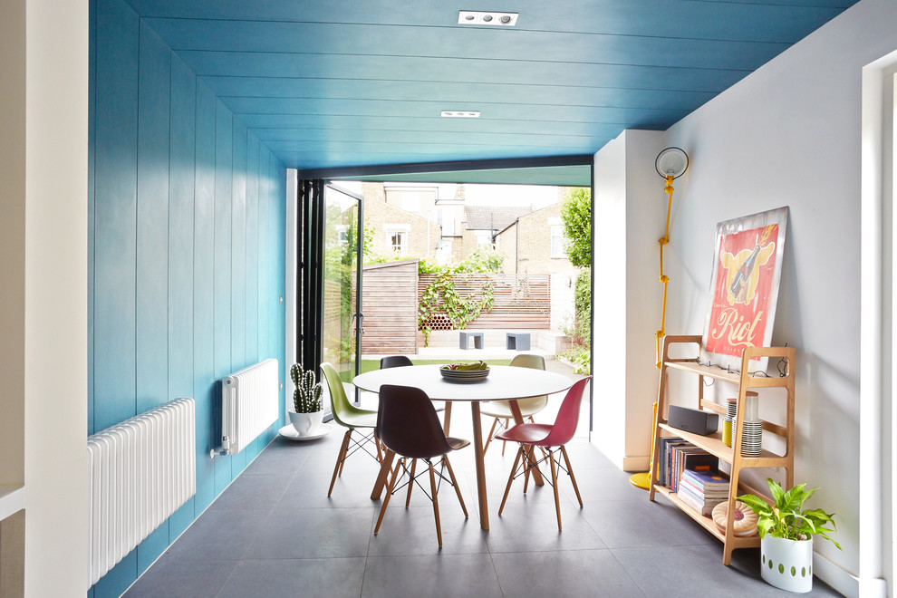 Photo of a mid-sized contemporary separate dining room in London with blue walls, no fireplace and grey floor.