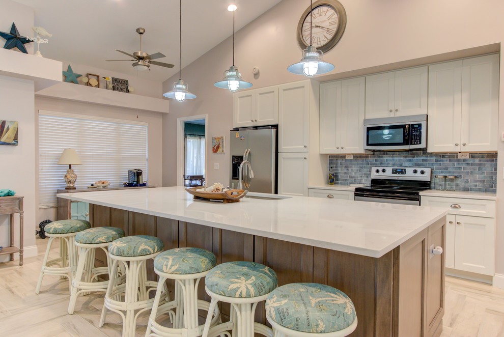 Inspiration for a large single-wall porcelain tile and white floor open concept kitchen remodel with an undermount sink, shaker cabinets, white cabinets, quartz countertops, blue backsplash, stainless steel appliances, an island and white countertops