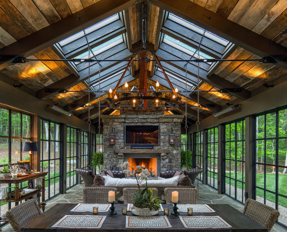 Large country sunroom in Charlotte with a stone fireplace surround, a skylight and green floor.