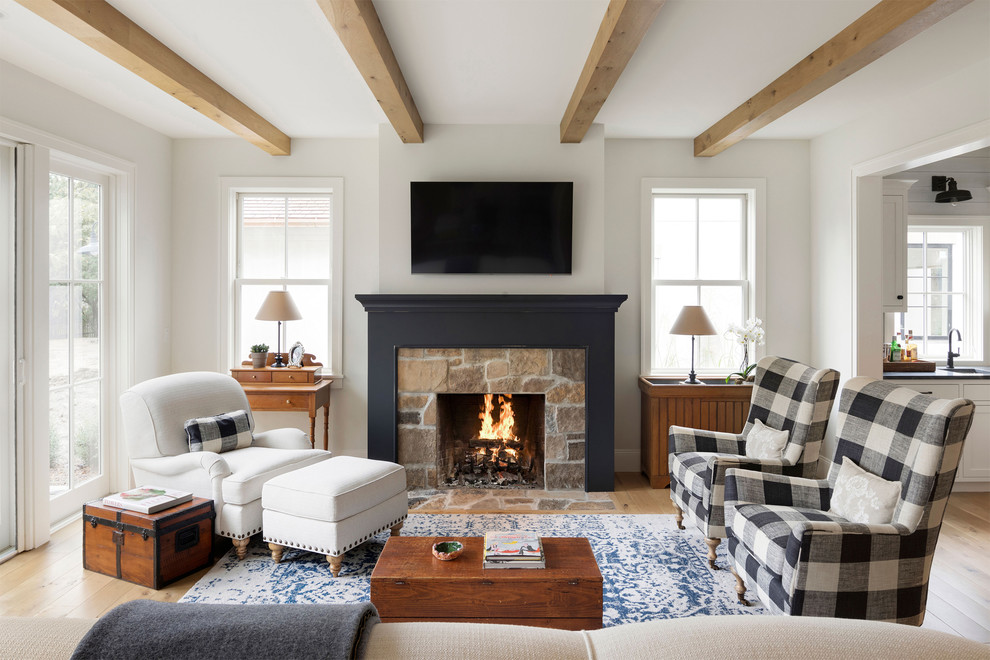 Inspiration for a country living room in Minneapolis with white walls, medium hardwood floors, a standard fireplace, a stone fireplace surround and brown floor.