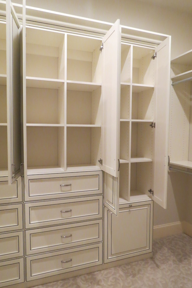 This is an example of a large traditional women's walk-in wardrobe in Atlanta with distressed cabinets, carpet and recessed-panel cabinets.