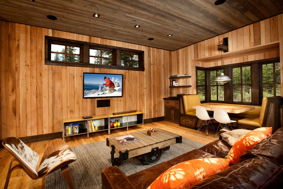 Photo of a country family room with brown walls, medium hardwood floors, a wall-mounted tv and brown floor.