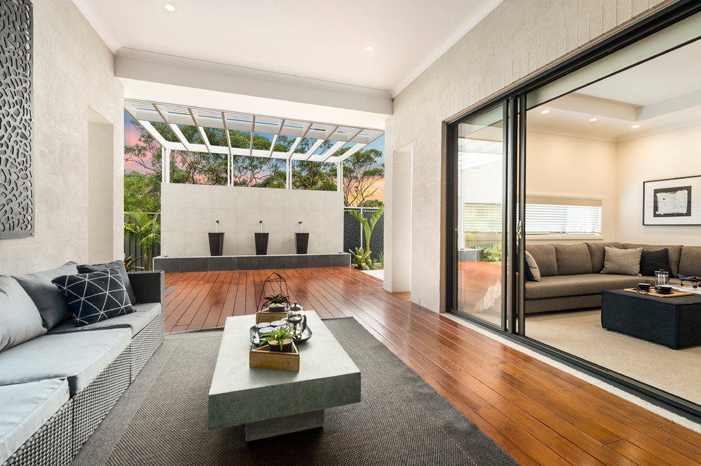 Photo of a large contemporary backyard deck in Sydney with a water feature and a roof extension.