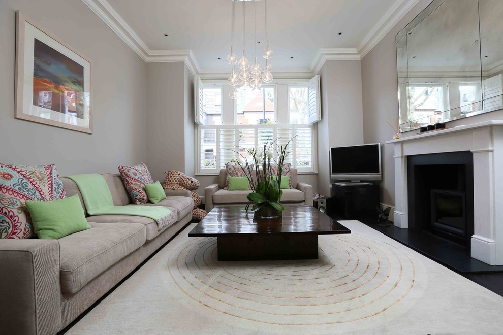 This is an example of a contemporary enclosed living room in London with grey walls, carpet, a standard fireplace, a plaster fireplace surround, a freestanding tv and beige floor.