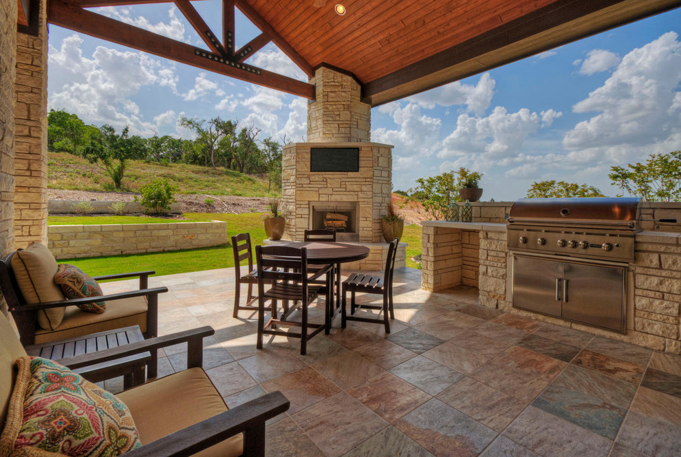 This is an example of a large contemporary backyard patio in Austin with an outdoor kitchen, tile and a roof extension.