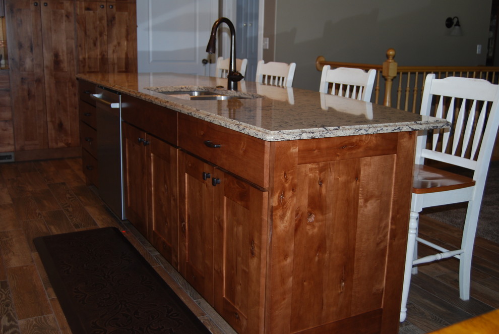 Inspiration for a mid-sized rustic l-shaped porcelain tile and brown floor eat-in kitchen remodel with an undermount sink, beaded inset cabinets, medium tone wood cabinets, beige backsplash, porcelain backsplash, an island, quartz countertops and stainless steel appliances