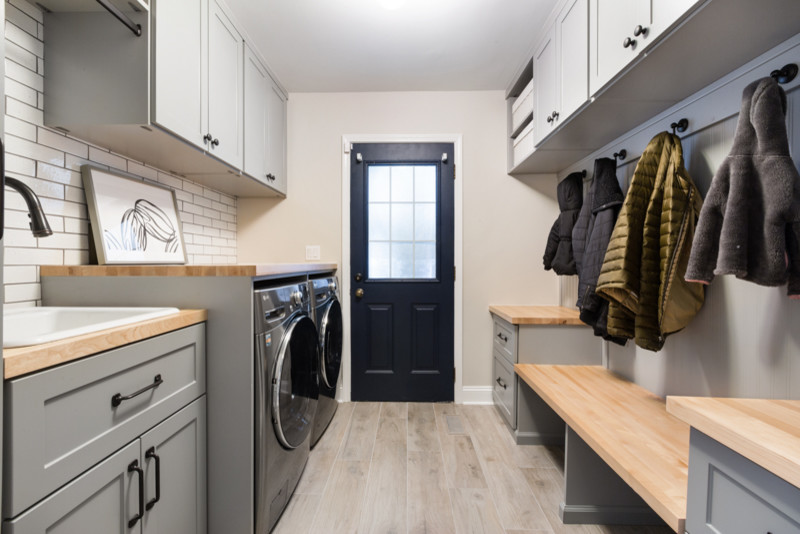 Inspiration for a mid-sized modern galley utility room in Chicago with a single-bowl sink, shaker cabinets, grey cabinets, wood benchtops, beige walls, ceramic floors, a side-by-side washer and dryer and beige benchtop.