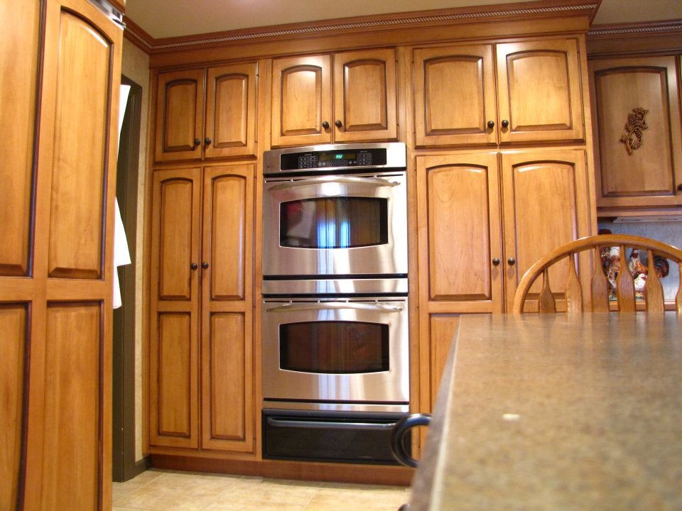 Example of a large minimalist ceramic tile and beige floor kitchen design with raised-panel cabinets, light wood cabinets, stainless steel appliances and an island