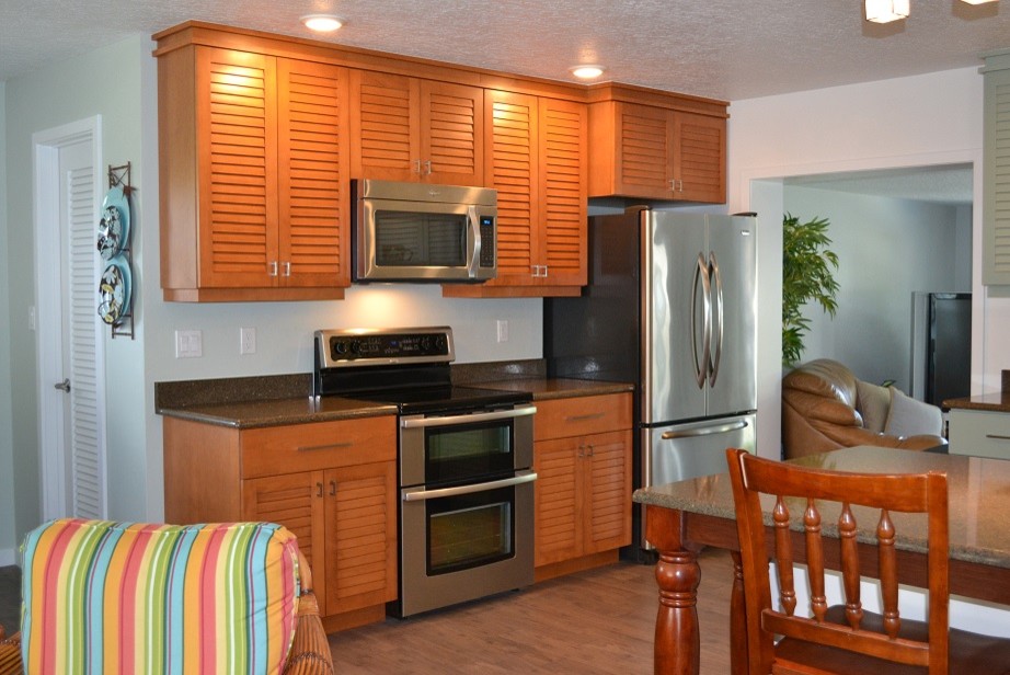 Photo of a mid-sized beach style l-shaped eat-in kitchen in Orlando with an undermount sink, louvered cabinets, medium wood cabinets, stainless steel appliances and with island.