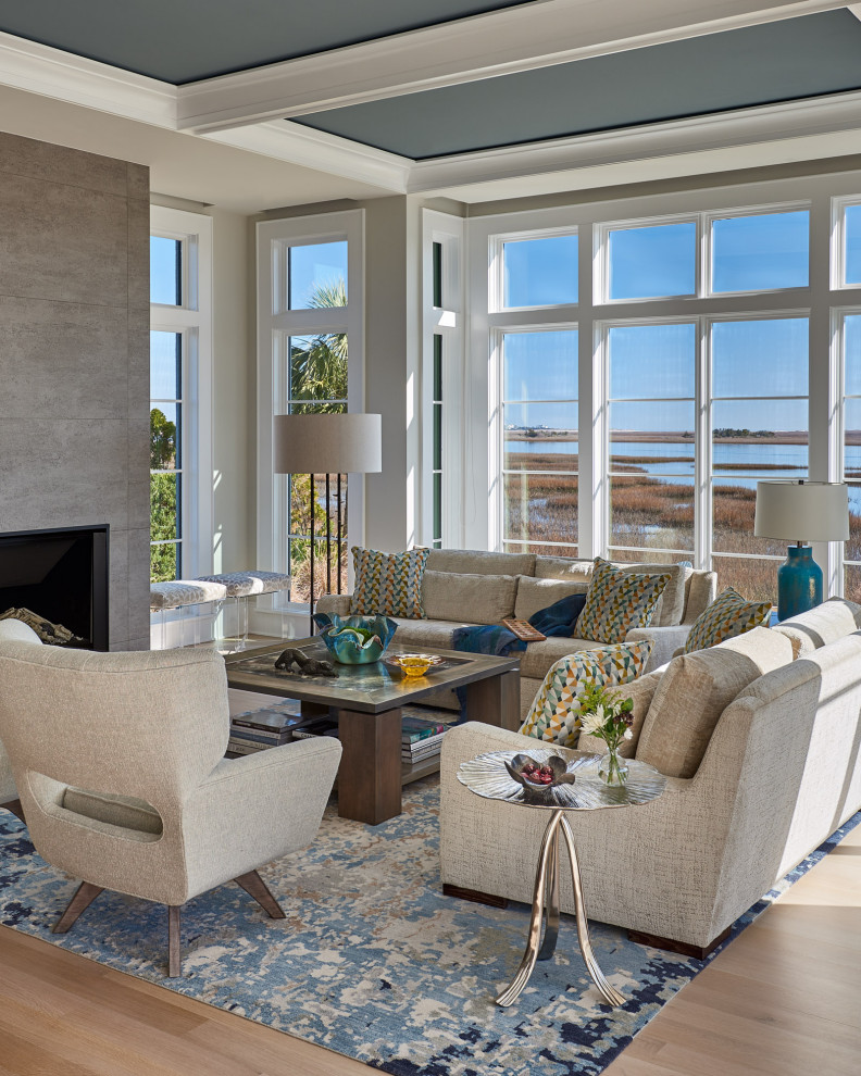 Photo of a large beach style open concept living room in Wilmington with white walls, light hardwood floors, a standard fireplace, a tile fireplace surround, a wall-mounted tv, beige floor and coffered.