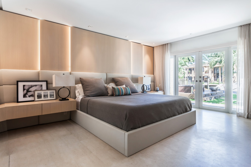 This is an example of a mid-sized contemporary master bedroom in Miami with limestone floors, white walls and grey floor.