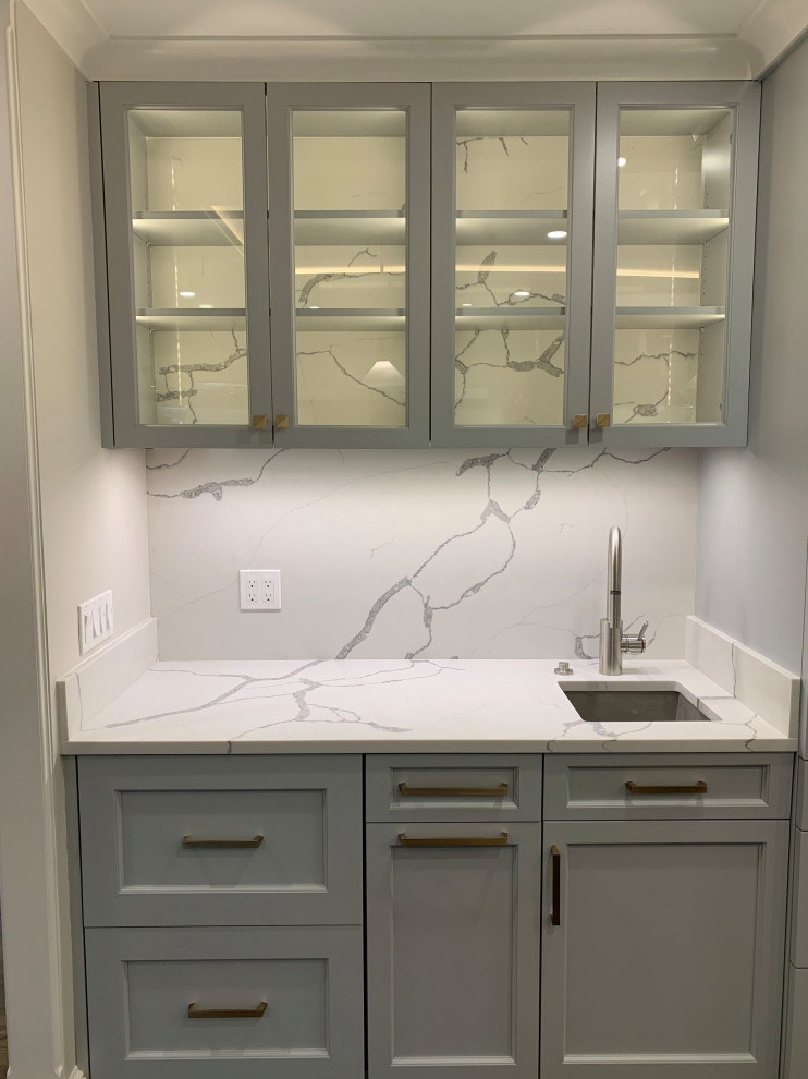 Large transitional galley dark wood floor and brown floor enclosed kitchen photo in Boston with a farmhouse sink, raised-panel cabinets, gray cabinets, quartzite countertops, white backsplash, stone slab backsplash, stainless steel appliances, an island and white countertops