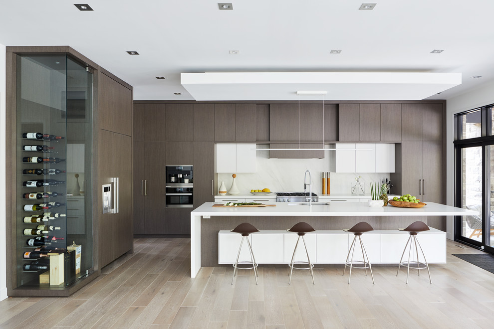 Contemporary single-wall kitchen in Toronto with flat-panel cabinets, dark wood cabinets, grey splashback, black appliances, light hardwood floors, with island and beige floor.
