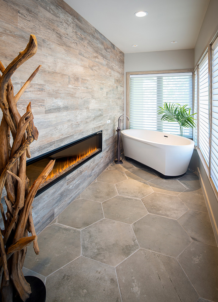 Inspiration for a beach style master bathroom in Sacramento with flat-panel cabinets, beige cabinets, a freestanding tub, a double shower, a one-piece toilet, gray tile, porcelain tile, grey walls, porcelain floors, a vessel sink, solid surface benchtops, grey floor, a hinged shower door and grey benchtops.