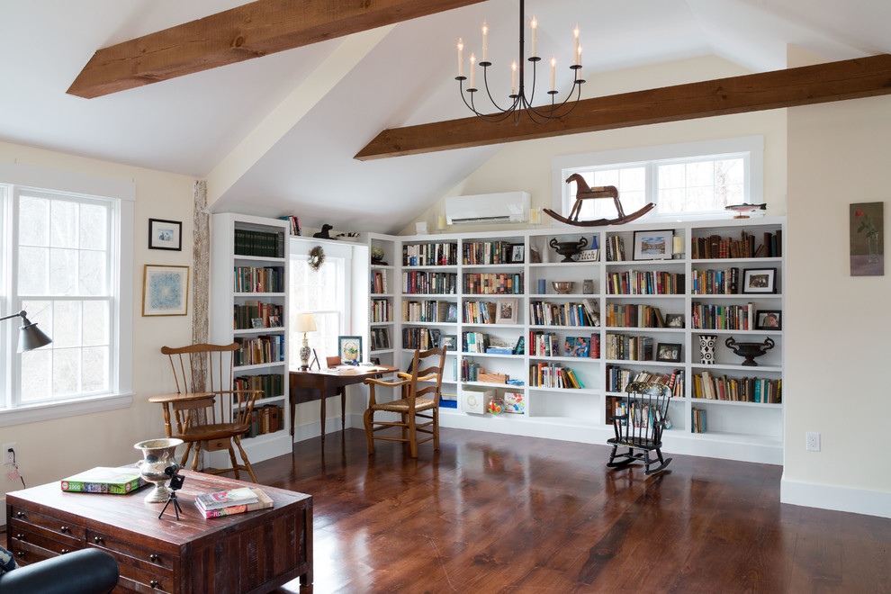 This is an example of a large country open concept family room in Boston with a library, beige walls, brown floor, dark hardwood floors and no fireplace.