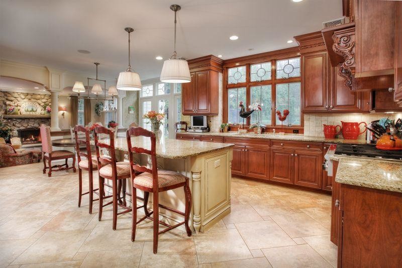 This is an example of a mid-sized transitional u-shaped eat-in kitchen in Las Vegas with raised-panel cabinets, beige cabinets, granite benchtops, beige splashback, stone slab splashback, panelled appliances, travertine floors and with island.