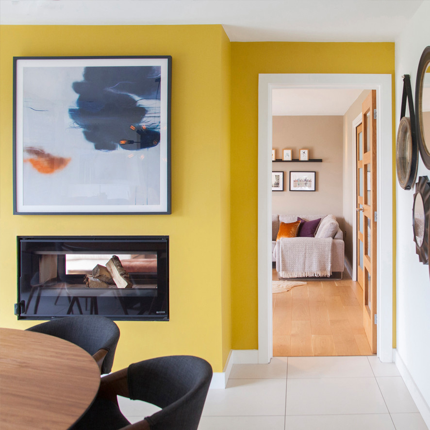 На фото: столовая в стиле модернизм с желтыми стенами, полом из керамической плитки, двусторонним камином и фасадом камина из металла с