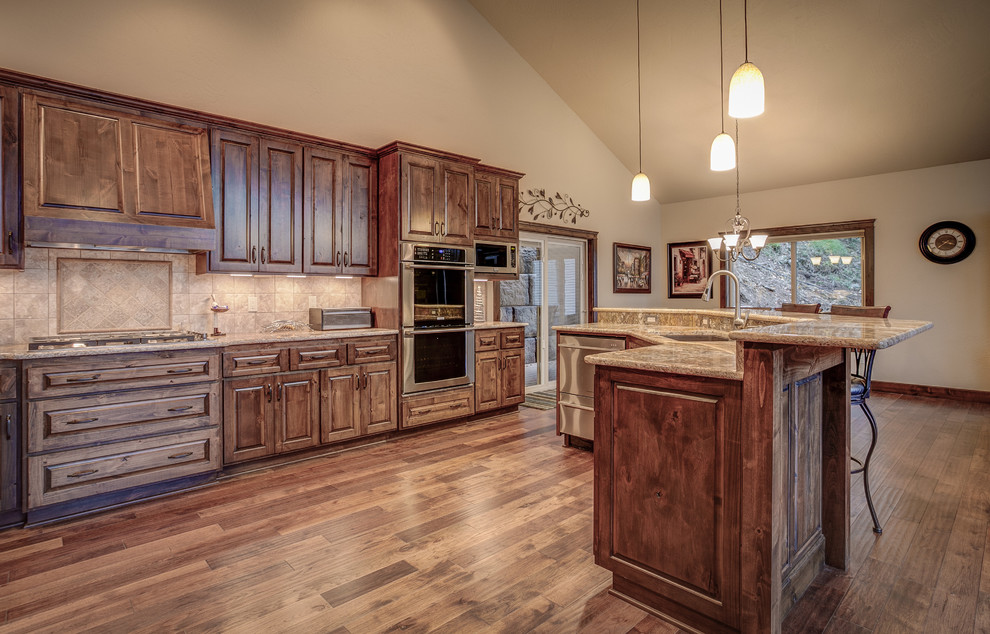 Photo of a large country u-shaped eat-in kitchen in Seattle with an undermount sink, raised-panel cabinets, medium wood cabinets, granite benchtops, beige splashback, ceramic splashback, stainless steel appliances, medium hardwood floors and with island.