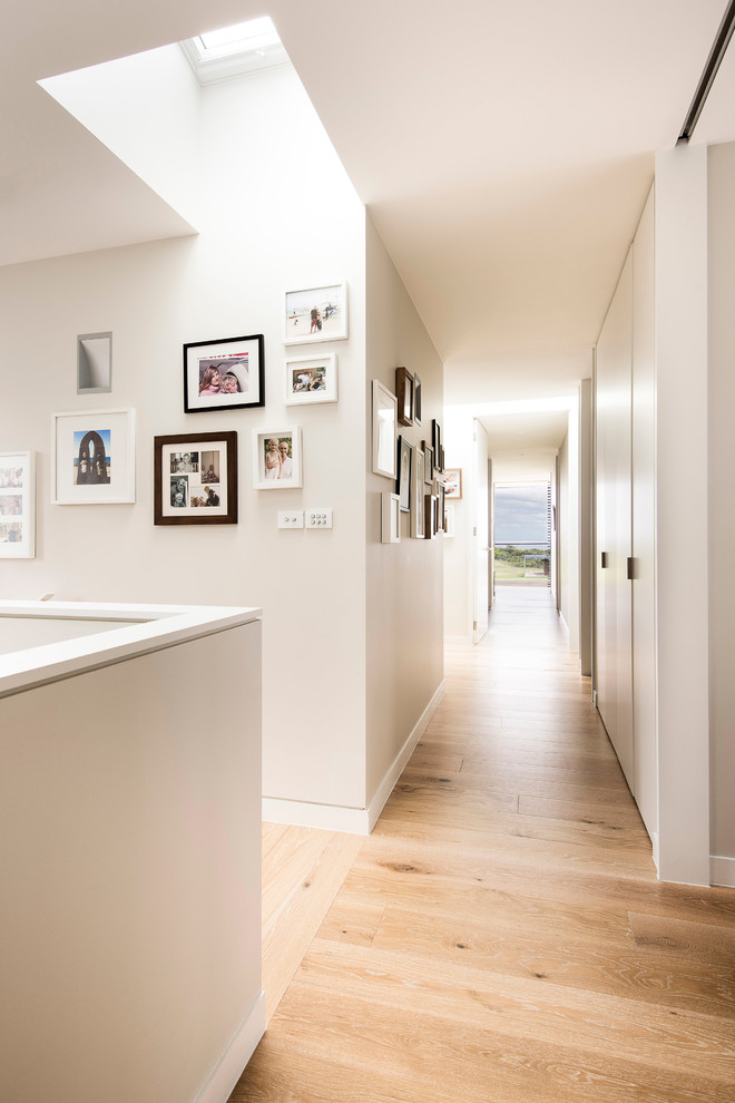 This is an example of a contemporary hallway in Sydney with beige walls and light hardwood floors.